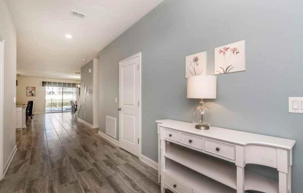 A hallway with a white console table, a door, and artwork on the wall.