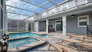 A pool area with a glass-enclosed patio, lounge chairs, and a hot tub. - 9032hs-the Retreat at Championsgate (Davenport)