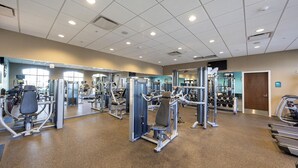 A gym with various exercise machines, a mirror, and a door. - 2404tgd Non Renting 11/28/2022 - Windsor at Westside (Kissimmee)
