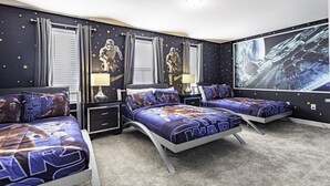 Une chambre décorée sur le thème de Star Wars, avec un grand lit agrémenté d’oreillers assortis, un plus petit lit et une fresque murale.