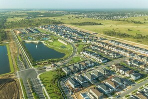 An aerial view of a residential area with houses, roads, and a large body of water.