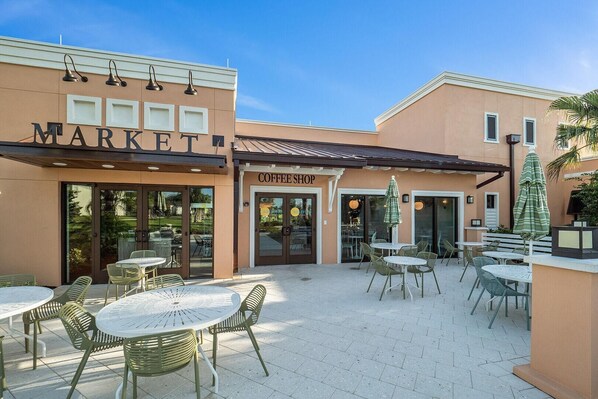 A coffee shop with outdoor seating and a market adjacent to it.