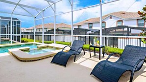 Un espacio al aire libre techado con piscina, sillas de descanso y vistas a edificios residenciales.