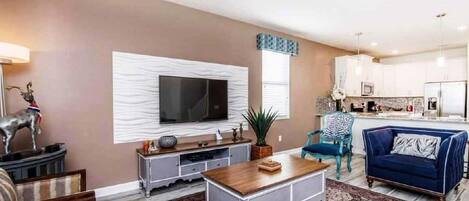 A living room with a flat-screen TV, a coffee table, and a sofa.