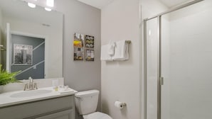 A bathroom with a white sink, toilet, and shower. There are wall-mounted towel racks and a mirror above the sink.