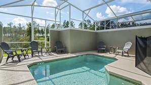 A covered outdoor pool area with chairs and tables, surrounded by a glass enclosure.