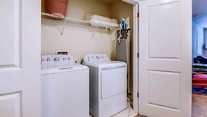 A laundry room with two white washing machines, a drying rack, and a basket on the wall. - 1516fd-the Retreat at Championsgate (Davenport)