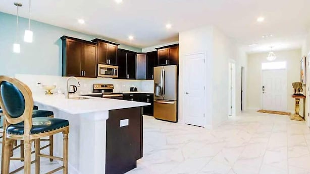 A modern kitchen with dark cabinets, a large island, and stainless steel appliances. - 1516fd-the Retreat at Championsgate (Davenport)
