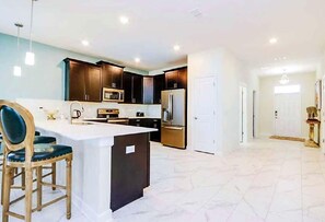 A modern kitchen with dark cabinets, a large island, and stainless steel appliances.