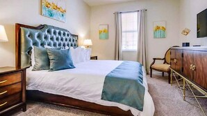 A bedroom with a large bed, a wooden headboard, a nightstand, a dresser, and a television. - 1516fd-the Retreat at Championsgate (Davenport)