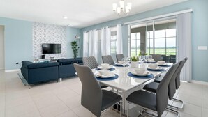 A modern dining area with a long table, chairs, and a television in the background. - 6082bod-solterra Resort (Davenport)