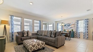 En stue med en hjørnesofa, skammel og et spisebord med stole.