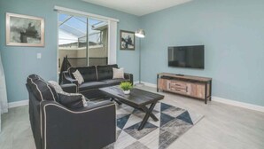 A living room with a black sofa set, a coffee table, a TV, and a wooden cabinet. - C550pbd- The Retreat at Championsgate (Davenport)