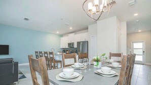 A modern dining area with a rectangular table set for four, surrounded by wooden chairs. - C550pbd- The Retreat at Championsgate (Davenport)