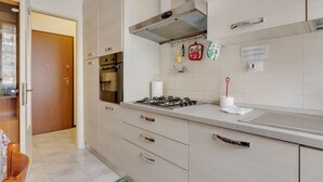 A modern kitchen with a gas stove, oven, and stainless steel range hood. There are cabinets, a countertop, and a backsplash.