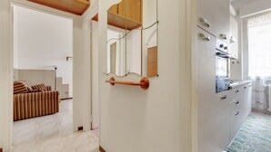 A modern kitchen with white cabinets, a built-in oven, and a stainless steel refrigerator.