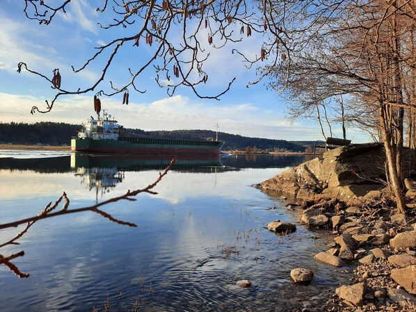 Un río tranquilo con un barco grande atracado a la izquierda, rodeado de costas rocosas y árboles.