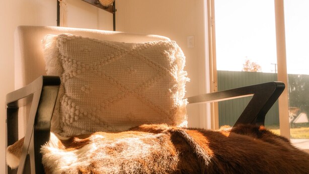 Une chaise avec un coussin texturé et une couverture douce et moelleuse.