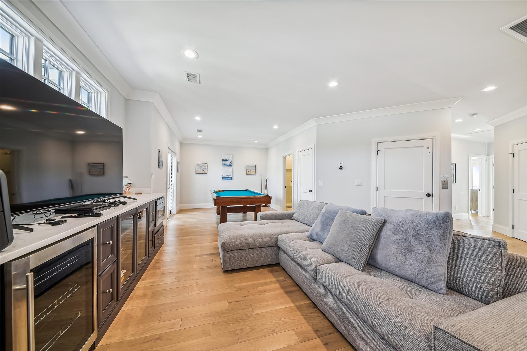 A modern kitchen with a built-in oven and a dining area with a pool table.