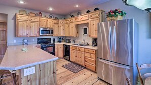 Cocina con armarios de madera, refrigerador de acero inoxidable e isla central.