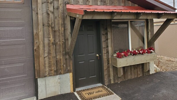 A wooden building with a dark door, a red awning, and a welcome mat. - Downtown Fairview BunkHouse (Fairview)