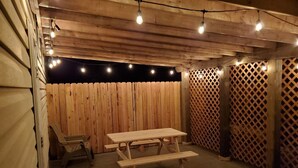A wooden deck with a picnic table and string lights. - Downtown Fairview BunkHouse (Fairview)