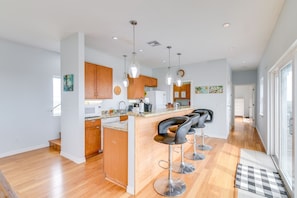 Enjoy meals and conversations at the central island with bar stools in this kitchen, featuring a large window and contemporary appliances.