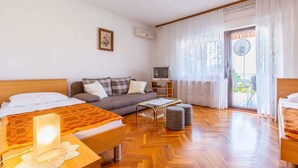 Une chambre d’hôtel avec deux lits, un canapé, une télévision et un balcon équipé d’une antenne parabolique.