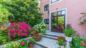 Un bâtiment doté d’un escalier en pierre menant à une porte, lequel est entouré de différentes plantes et fleurs en pot.