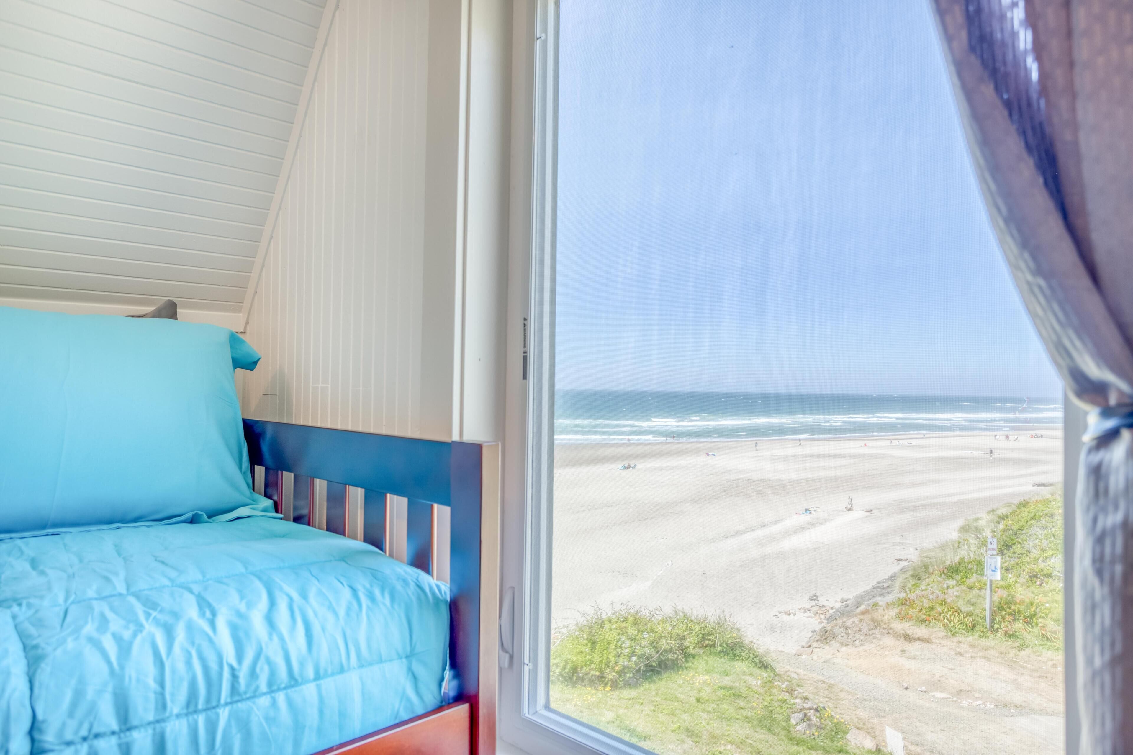 A bedroom with a bed, a window, and a view of the beach.