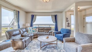 Un salon spacieux avec un canapé d’angle en cuir, une table basse ronde et un fauteuil bleu.