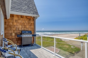 A balcony with a grill, wicker chairs, and a view of the beach. - Anchor Court (Lincoln City)