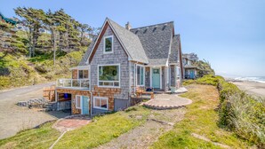 Une maison située sur la côte, dotée d’une grande terrasse, d’un garage et offrant une vue sur l’océan.