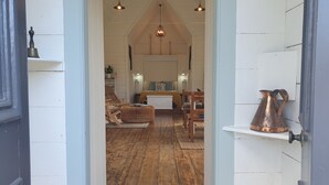 Ein gemütliches Zimmer mit Holzboden, einem Bett mit gelber Decke, einem Holzstuhl und einem kleinen Tisch.
