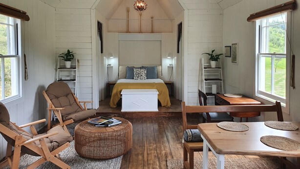 Ein gemütliches Zimmer mit einem Bett, zwei Stühlen, einem Tisch und einer Pendelleuchte.