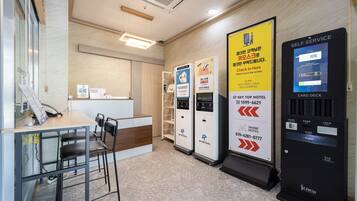 A hotel reception area with a self-service card machine, a reception desk, and a seating area.