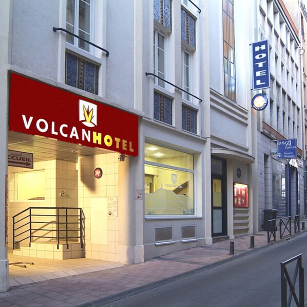 A hotel named VolcanHotel with a red sign, a visible entrance, and a staircase leading to the entrance.