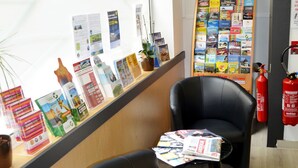 A reception area with a counter displaying brochures and a fire extinguisher. There are two black chairs and a small table with magazines. - Artyster Clermont-ferrand (Clermont-Ferrand)