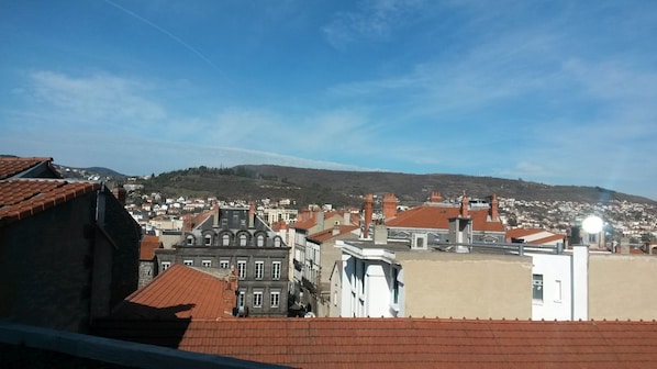 A cityscape with a mix of traditional and modern buildings, a clear sky, and a hilly background.
