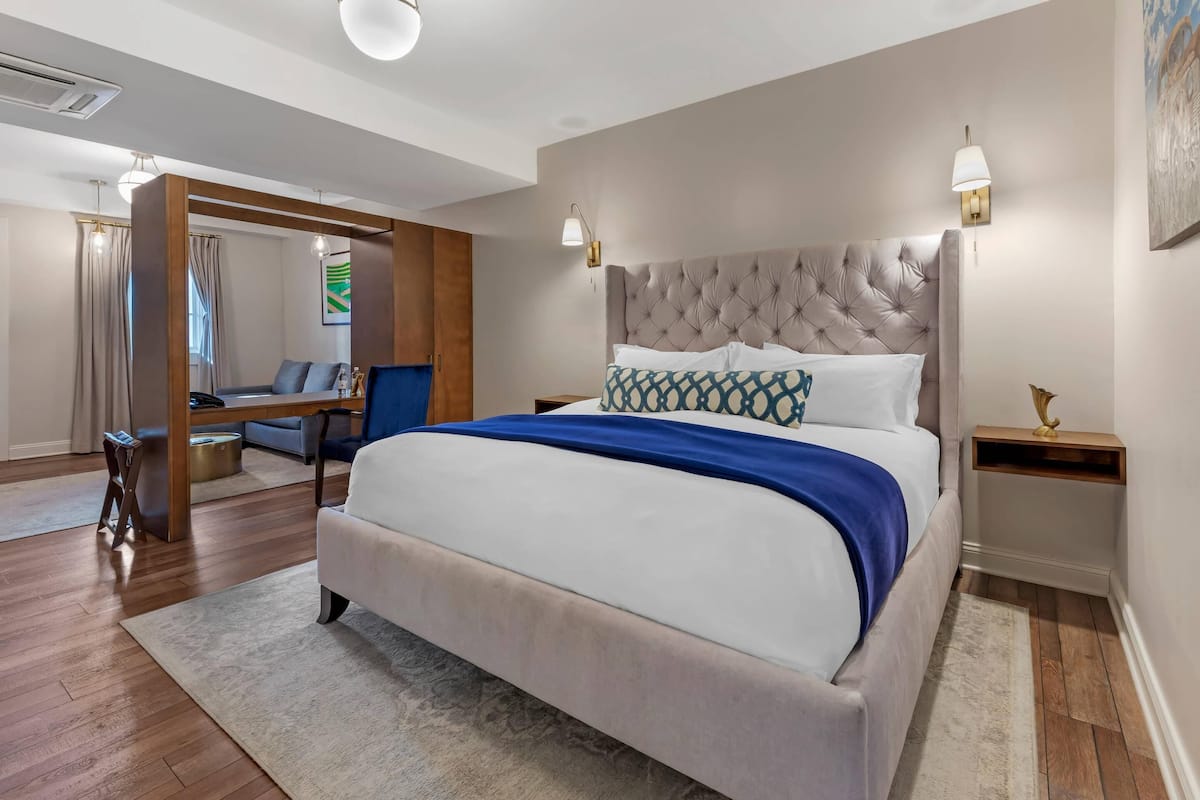 A modern bedroom with a large bed, a wooden desk, a chair, and a sofa.
