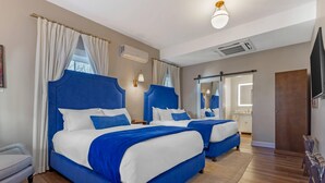 A hotel room with two beds, a sofa, a TV, and a bathroom visible through a door. - The Colonial Inn, an Ascend Collection Hotel (Hillsborough)