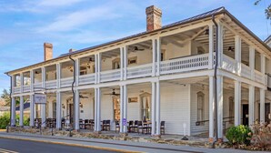 A colonial-style building with a covered porch, multiple windows, and outdoor seating. - The Colonial Inn, an Ascend Collection Hotel (Hillsborough)