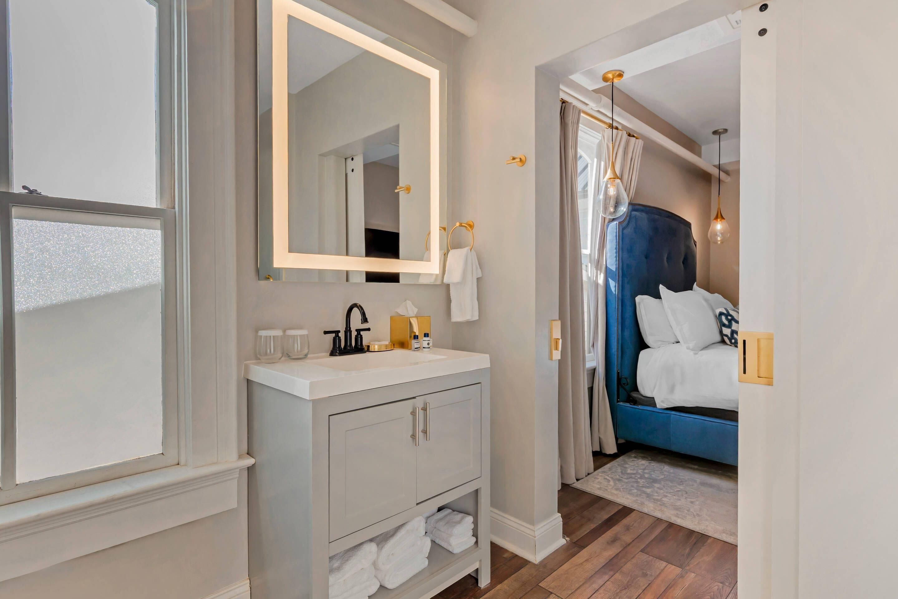 A bathroom with a mirror, sink, and towel rack.