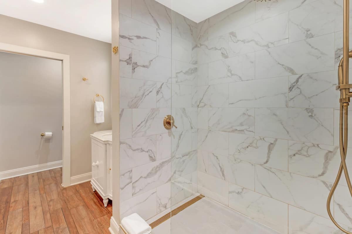 A bathroom with marble tiles, a shower, a toilet, and a vanity.