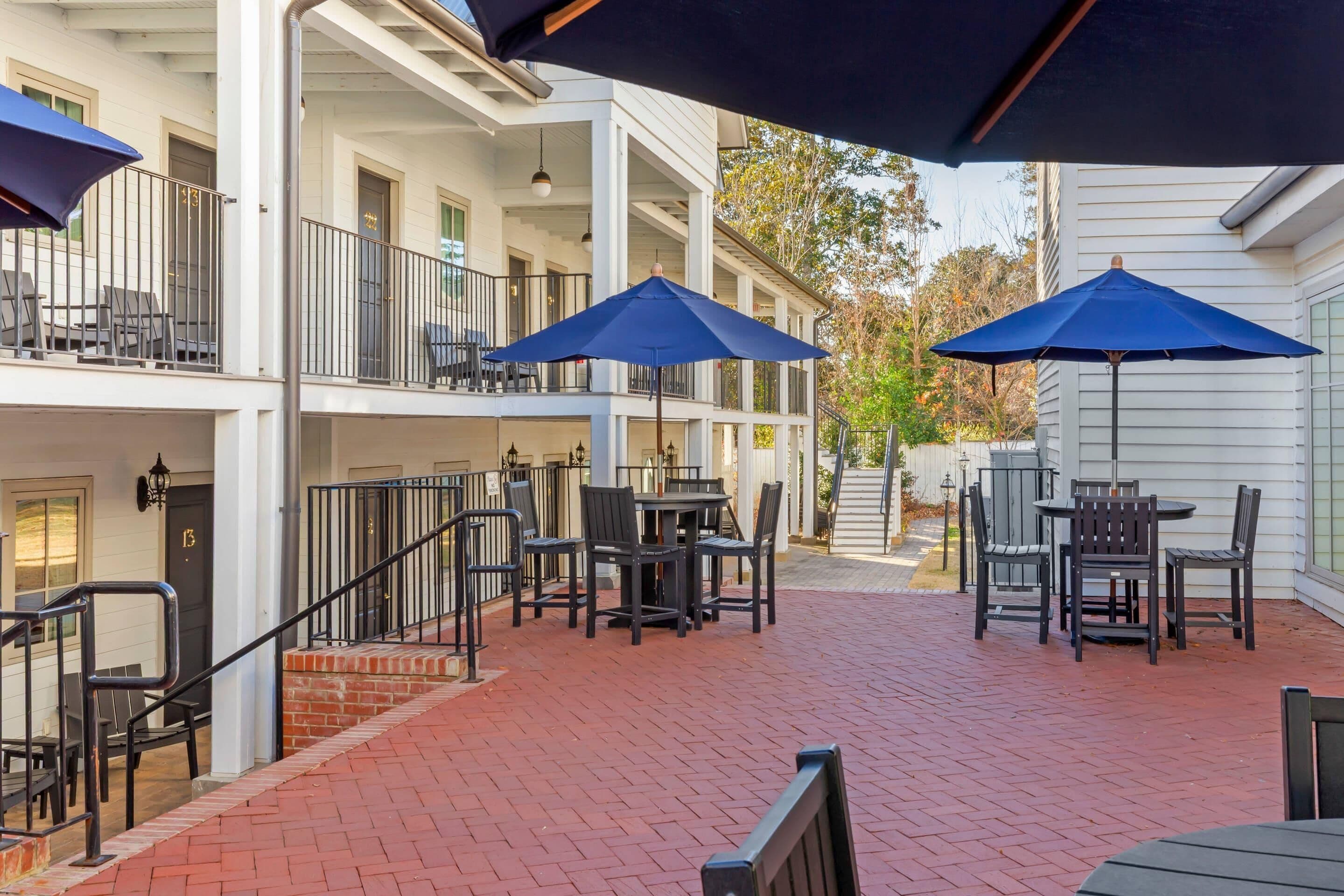 A courtyard with outdoor seating, a staircase, and a building with a balcony.