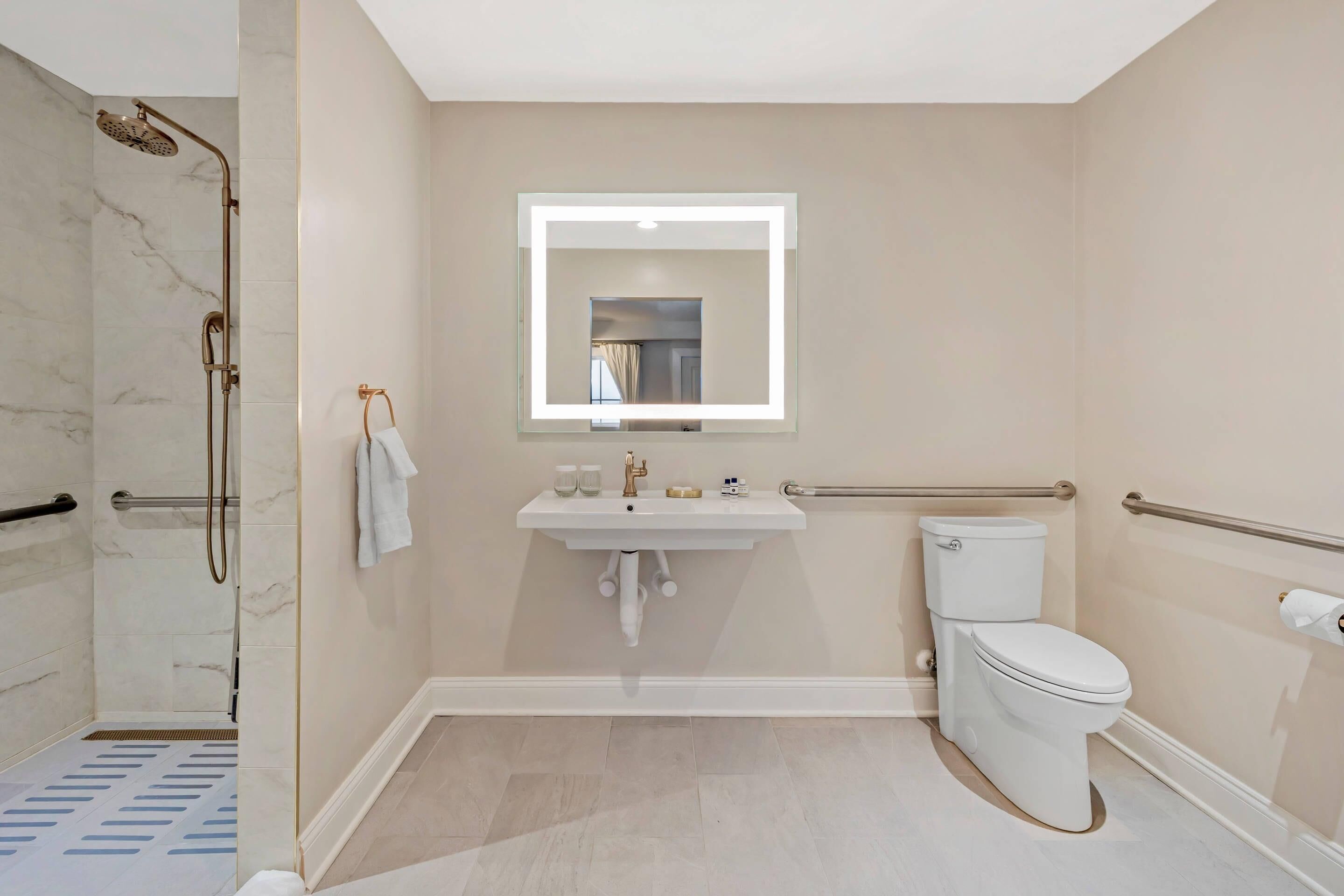 Une salle de bain équipée d’une douche, d’un lavabo, de toilettes et d’un miroir avec éclairage.