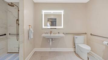 Une salle de bain équipée d’une douche, d’un lavabo, de toilettes et d’un miroir avec éclairage.