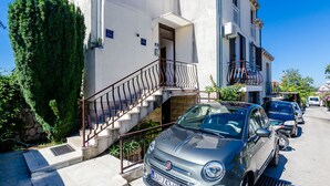 A parked silver car in front of a building with a staircase leading to a balcony. - Room Bruna - double room (Dubrovnik)