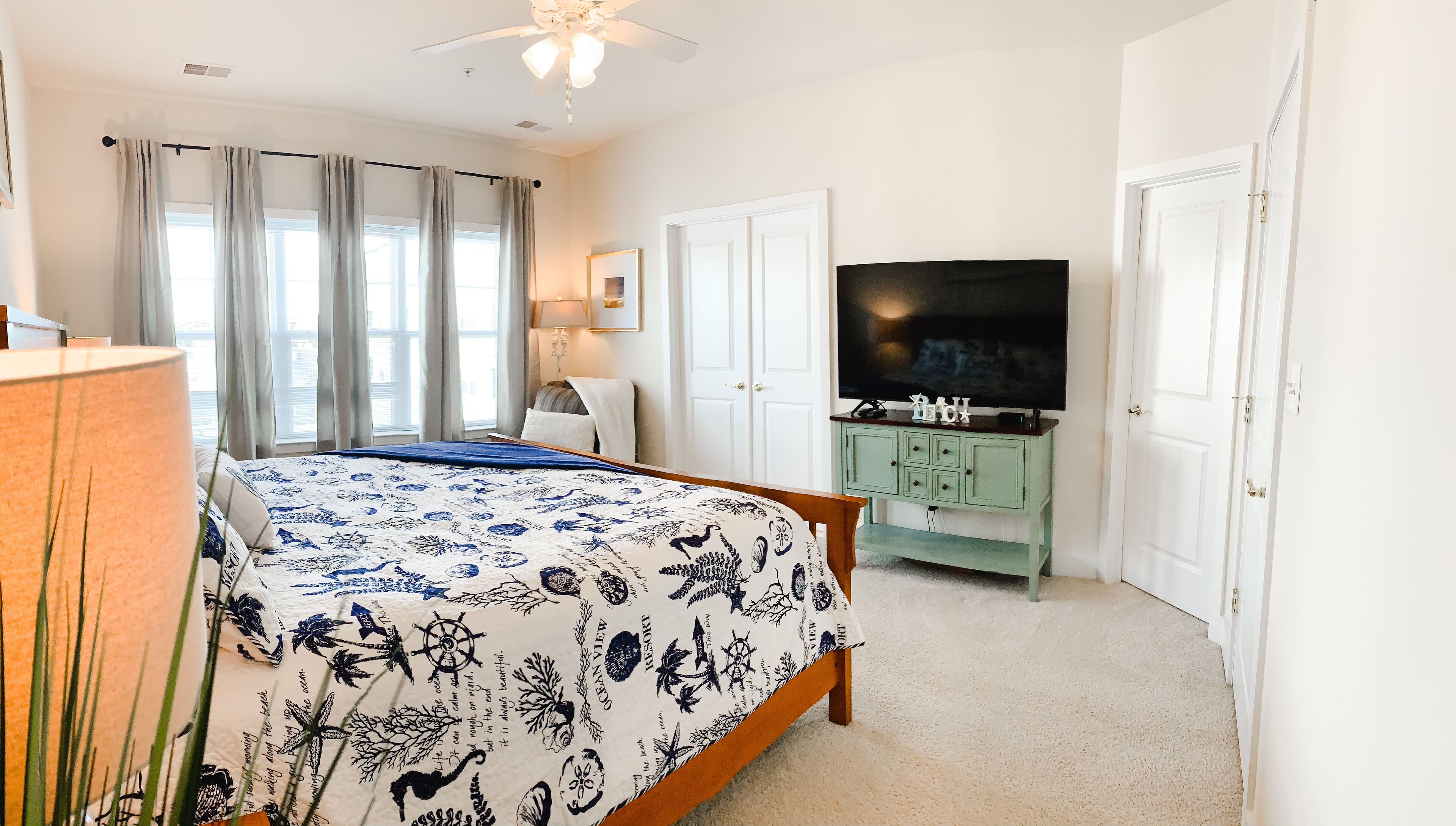 A bedroom with a bed, a television, a desk, and a cabinet.