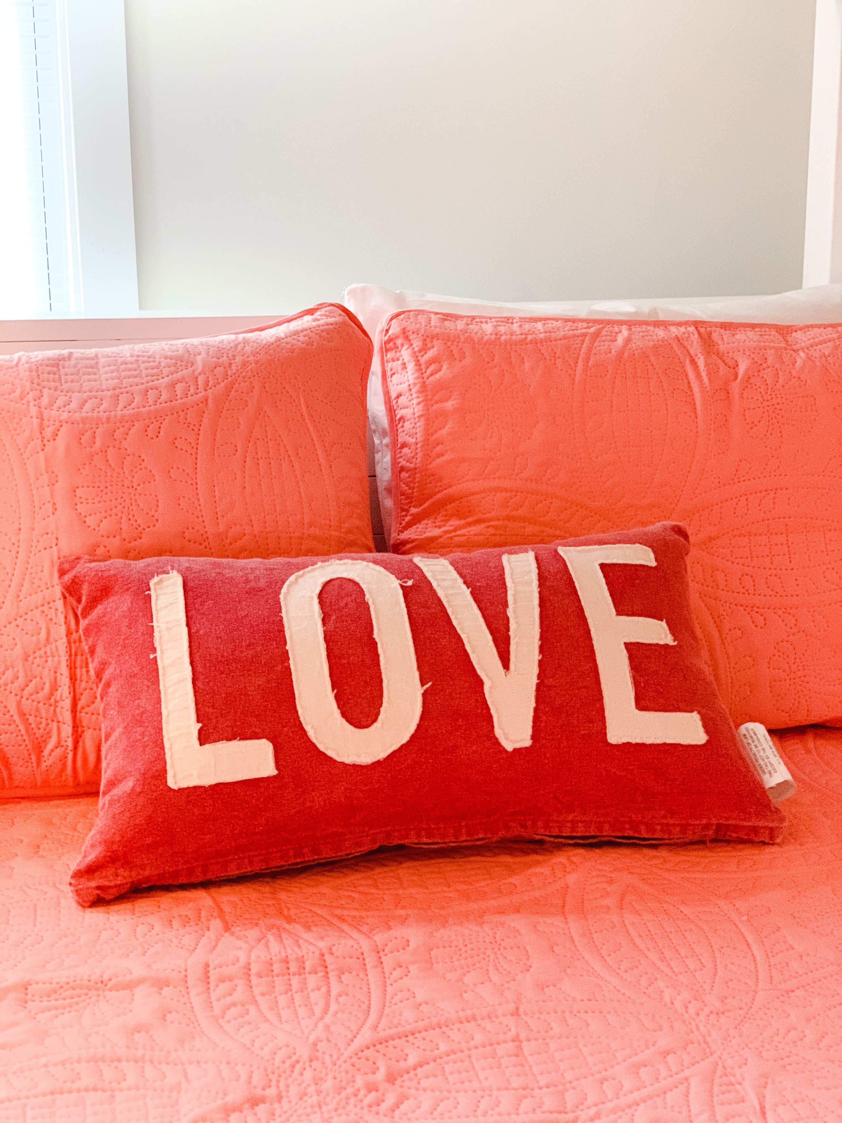A red couch with a pillow that has the word "LOVE" on it.